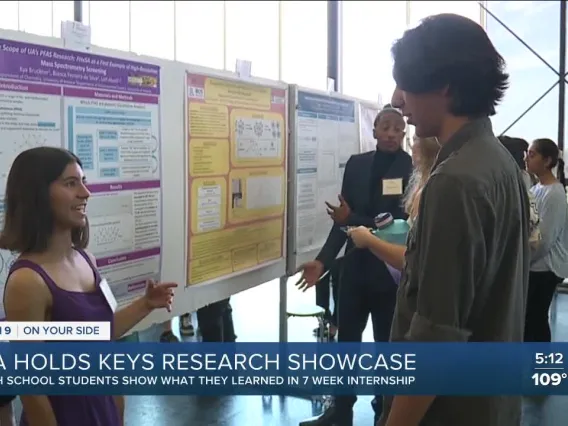 high school student presenting a research poster to a crowd of people