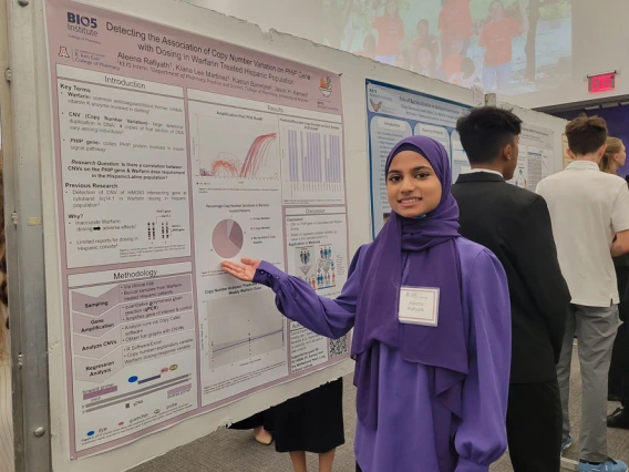 Young person in a purple headscarf gestures to her poster