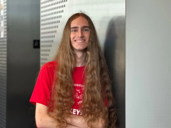 Person with long brown hair wearing a red KEYS tshirt smiles confidently 