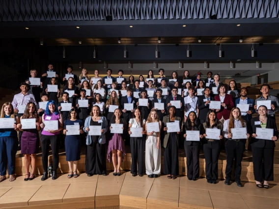Group of KEYS Research Internship graduates holding certificates in an auditorium, standing in several rows and smiling.