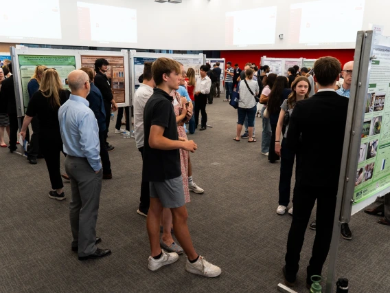 Attendees discussing academic posters at a university research showcase event.