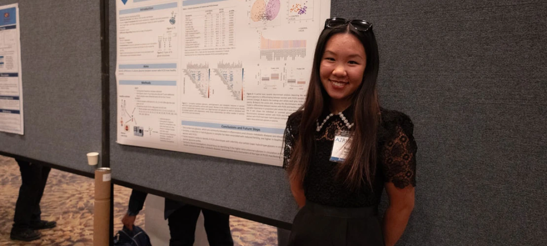 Person smiling in front of a research poster about Asperger's and Autistic savant syndrome at a scientific conference.