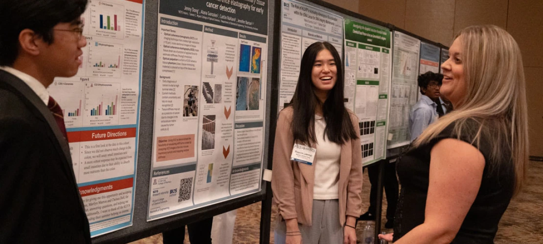 Three individuals standing by research posters, engaging in a discussion at a professional conference.