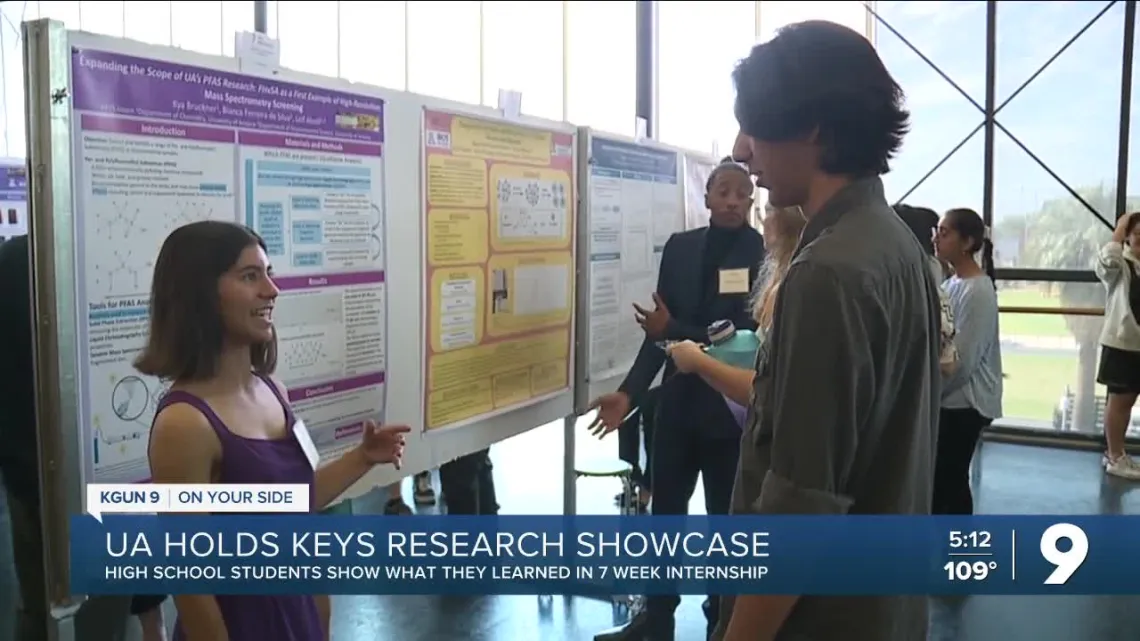 high school student presenting a research poster to a crowd of people