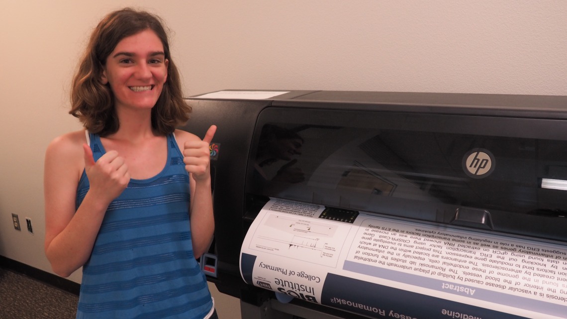 Young person with two thumbs up prints a large scientific poster