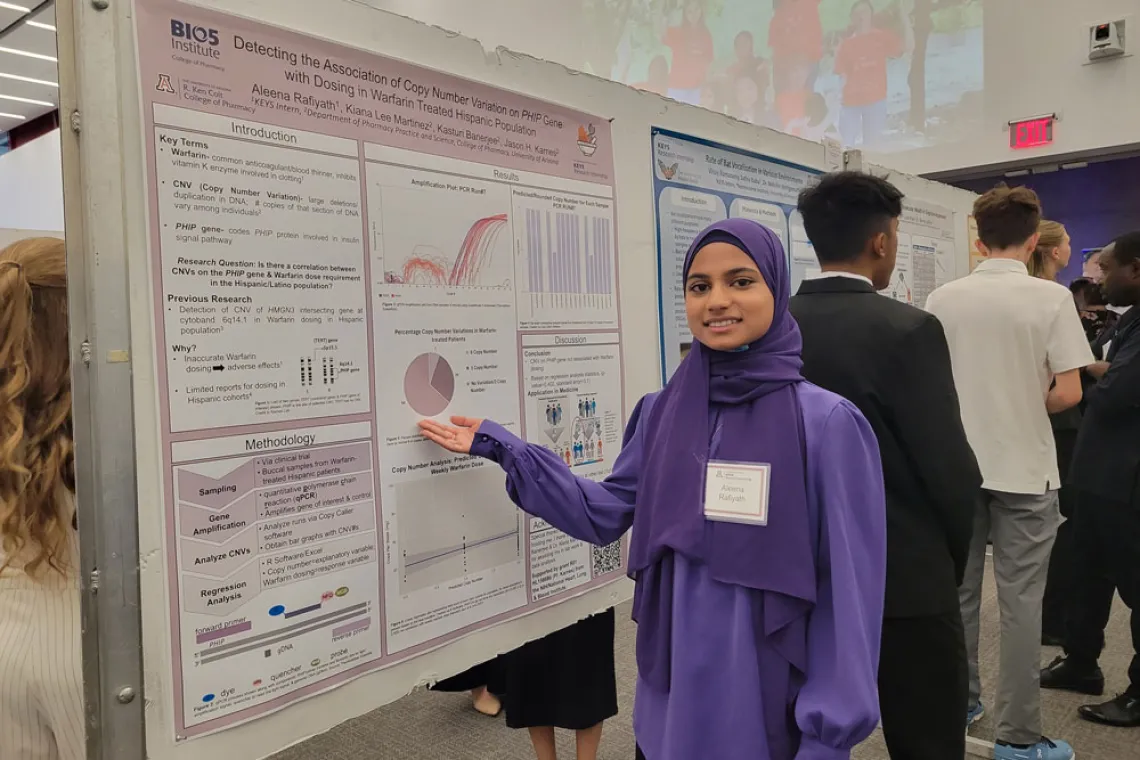 Young person in a purple headscarf gestures to her poster