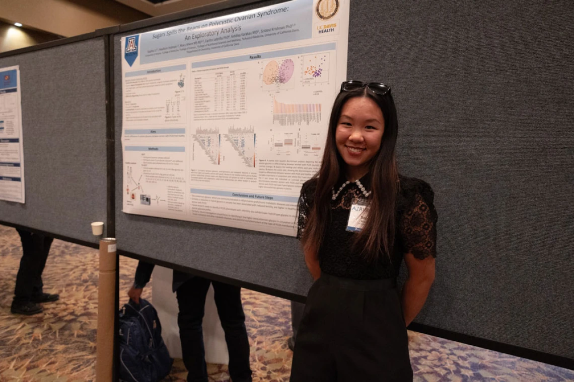 Person smiling in front of a research poster about Asperger's and Autistic savant syndrome at a scientific conference.