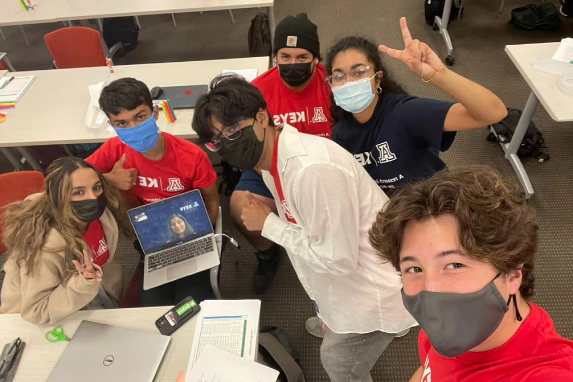 Group of young people wearing masks waving and giving peace signs for a selfie