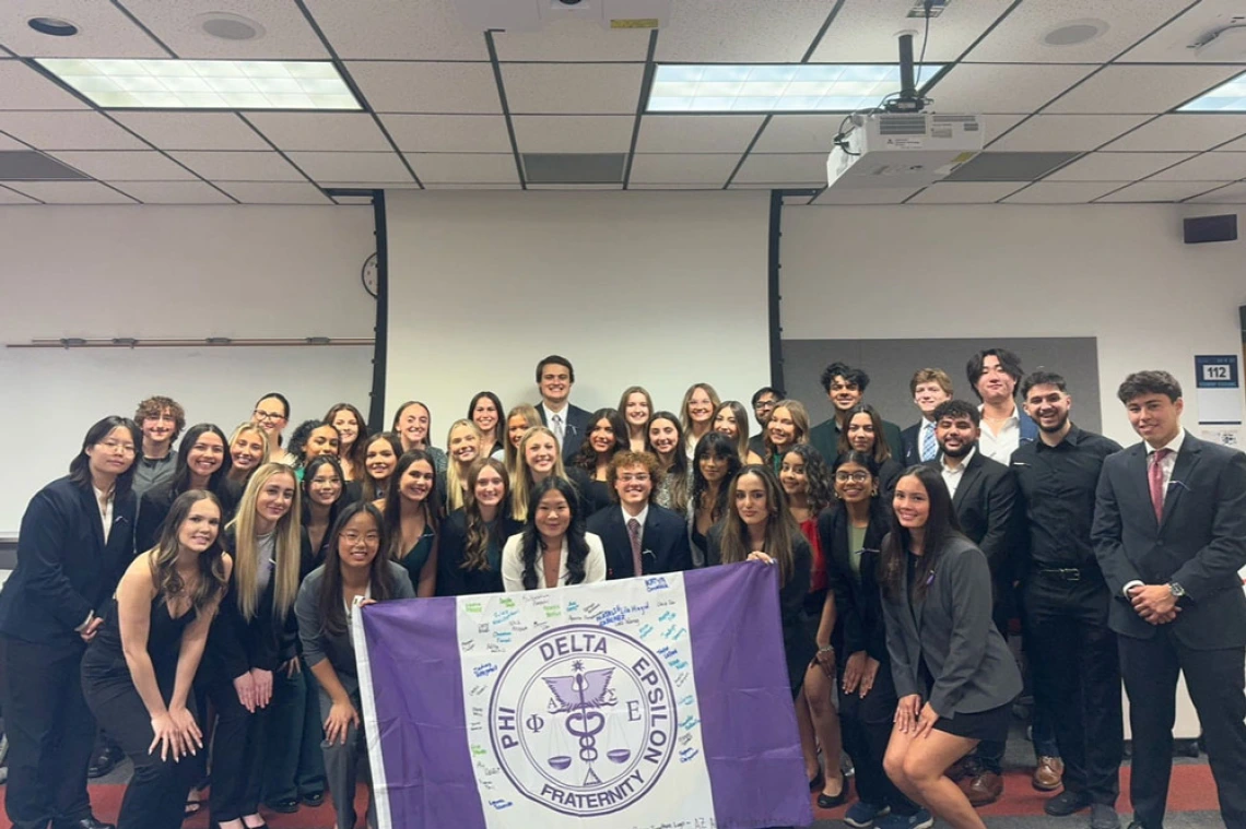 Large group of people pose with Phi Delta Epsilon sign