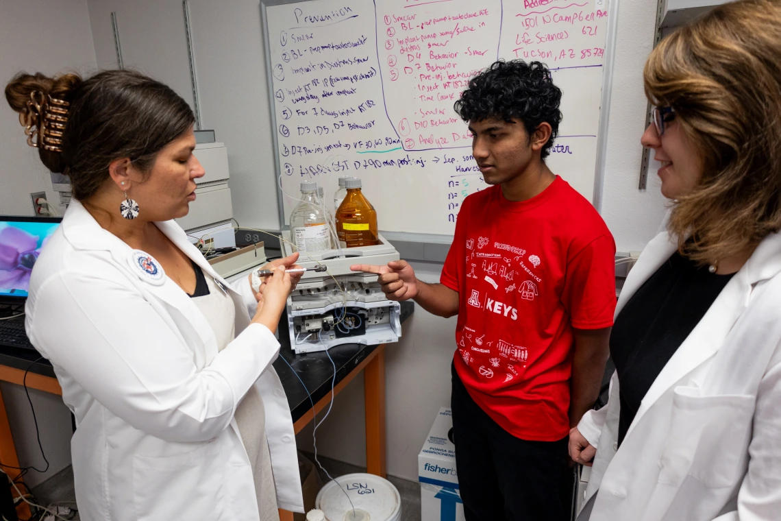 high school student working in a lab with 2 researchers
