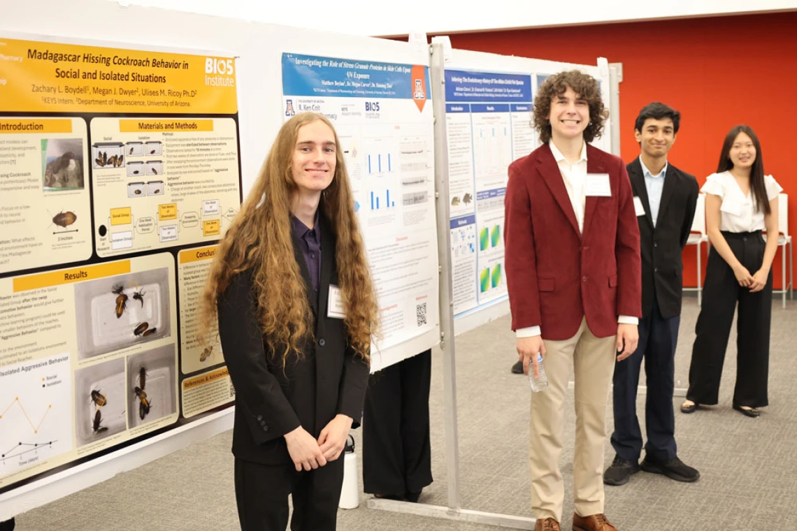 Group of young people in professional clothing stand in front of their posters