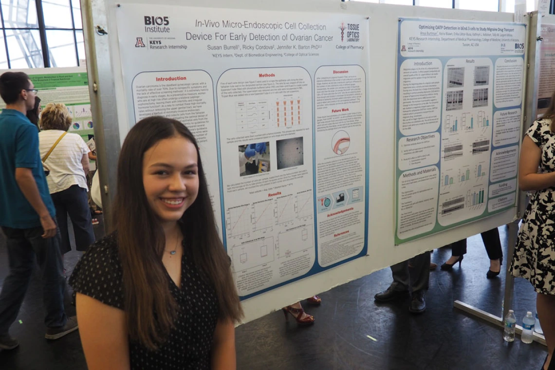 A person smiling at a science showcase, displaying a posters entitled "In Vivo Micro Endoscopic Cell Collection Device For Early Detection of Ovarian Cancer" at the BIO5 Institute.