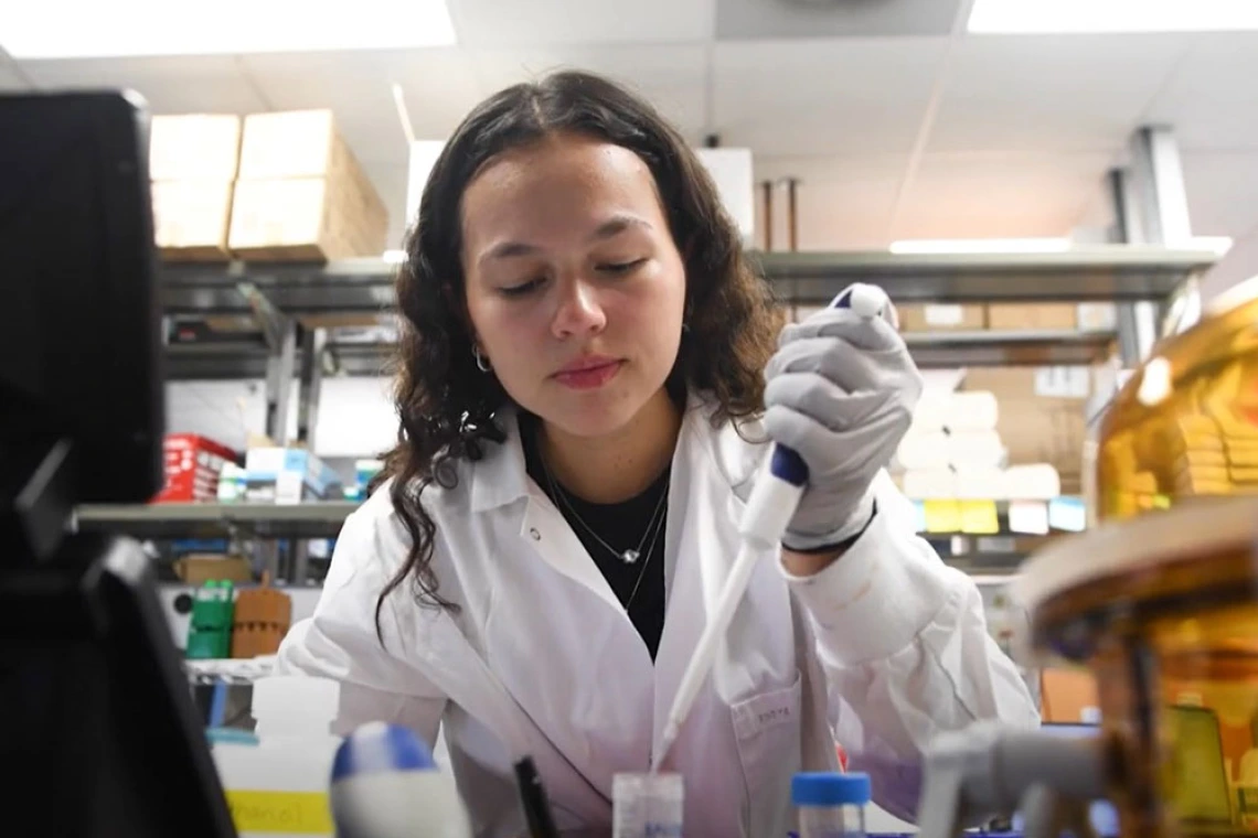Scientist conducting research in a laboratory, using a pipette to handle a sample.