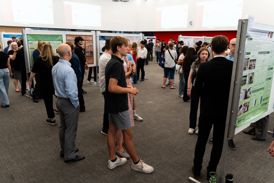 Attendees discussing academic posters at a university research showcase event.