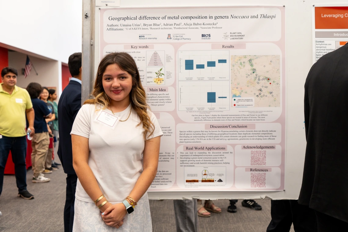Person presenting a scientific poster titled "Geographical difference of metal composition in genera Noctua and Thaspi" at a showcase.