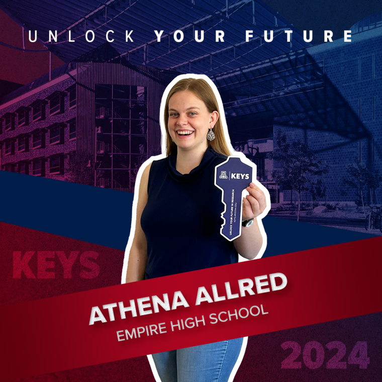 A high school student posing with a paper key in their hand