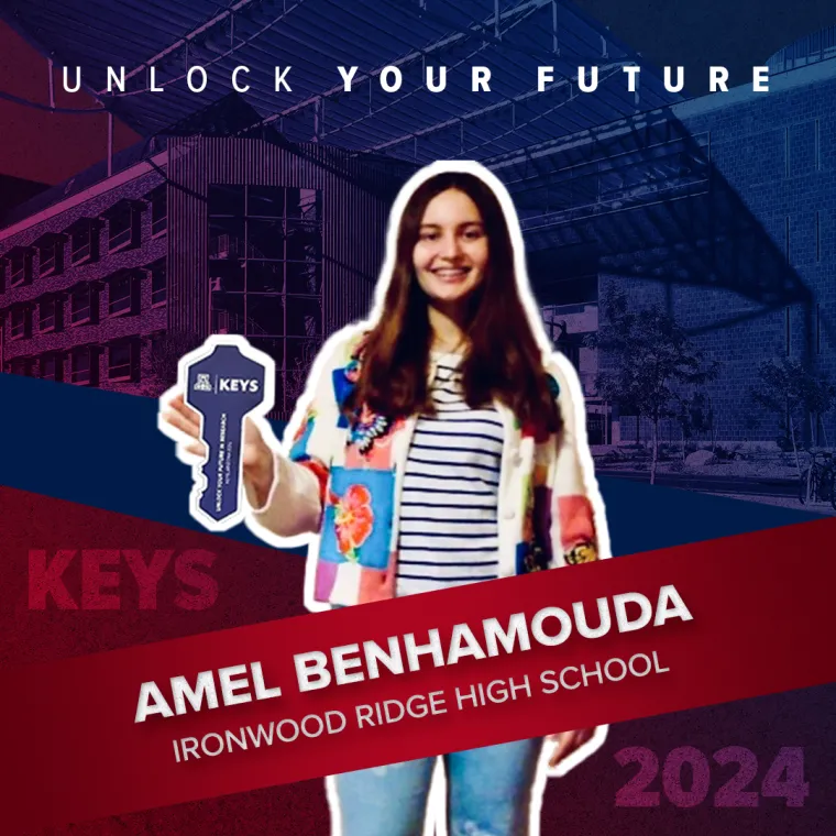 A high school student posing with a paper key in their hand