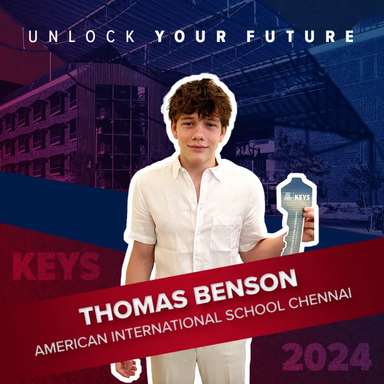A high school student posing with a paper key in their hand