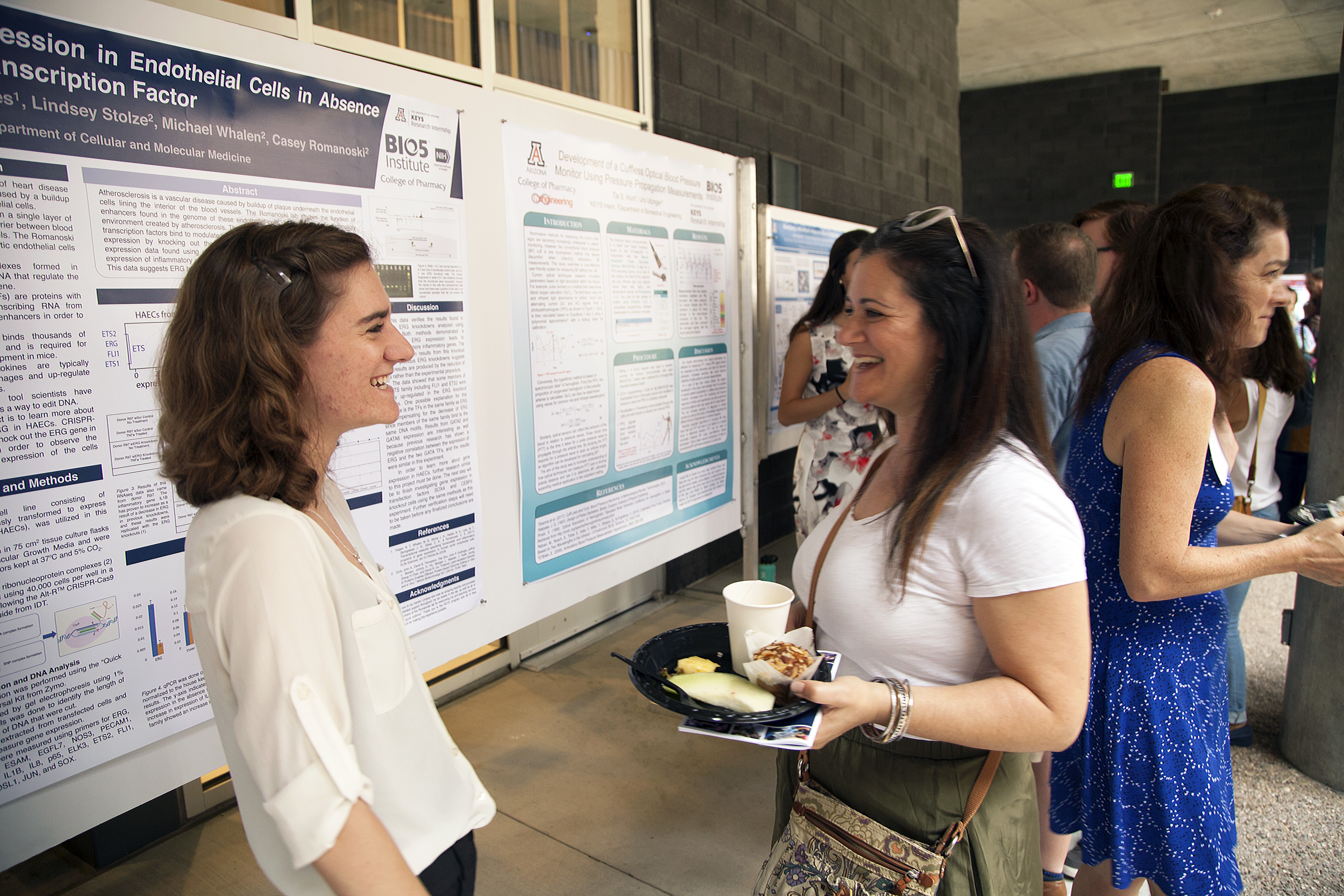 Two young people talk and laugh in front of a scientific poster