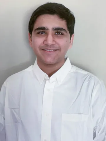 Portrait of a smiling person in a white shirt against a light-colored background.