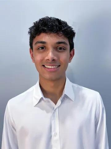 Portrait of a smiling person in a white shirt against a light-colored background.